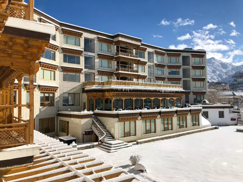 A hotel facade covered in snow with snow-capped peaks in the background