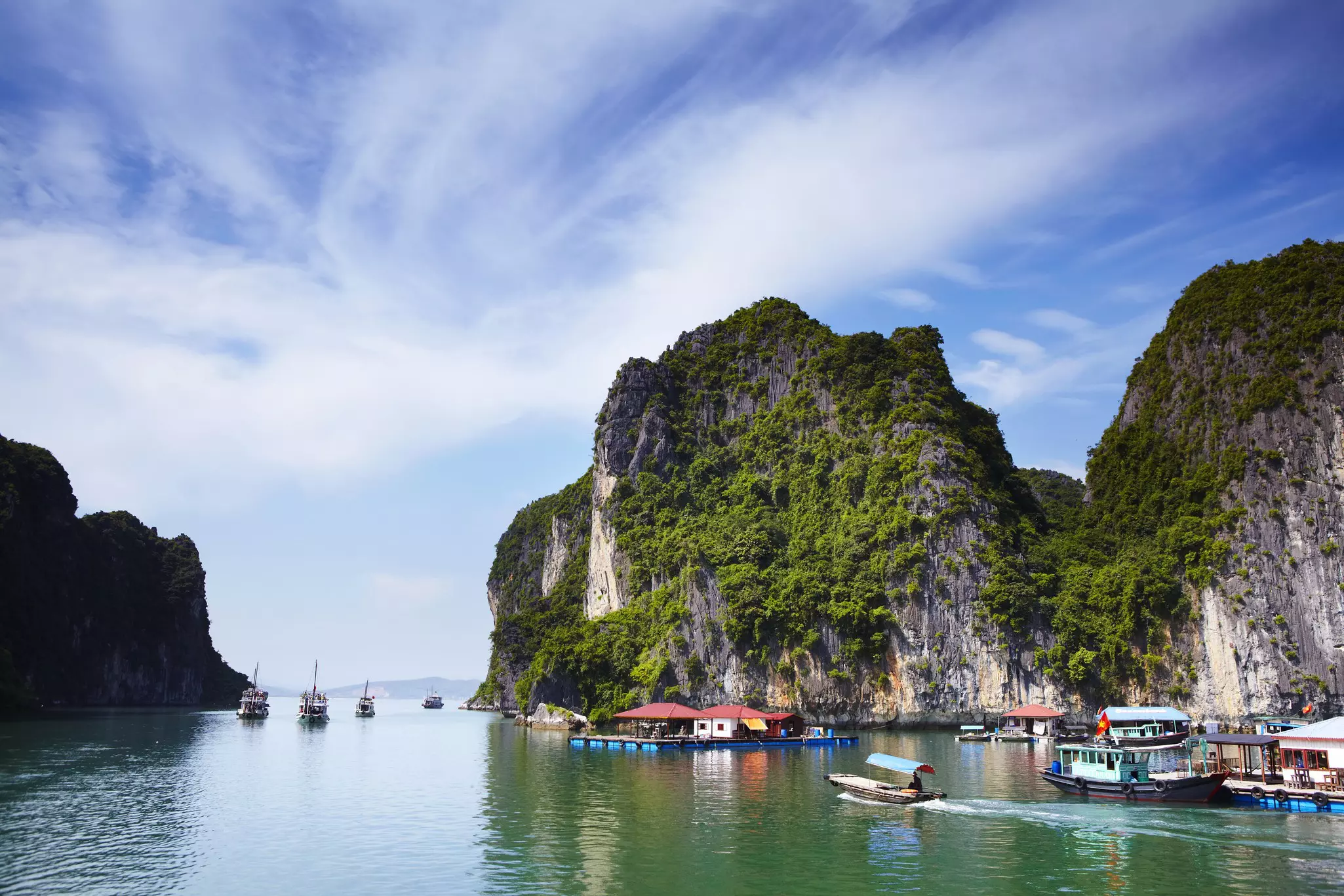 Boats pass limestone outcrops in Halong Bay, Vietnam.