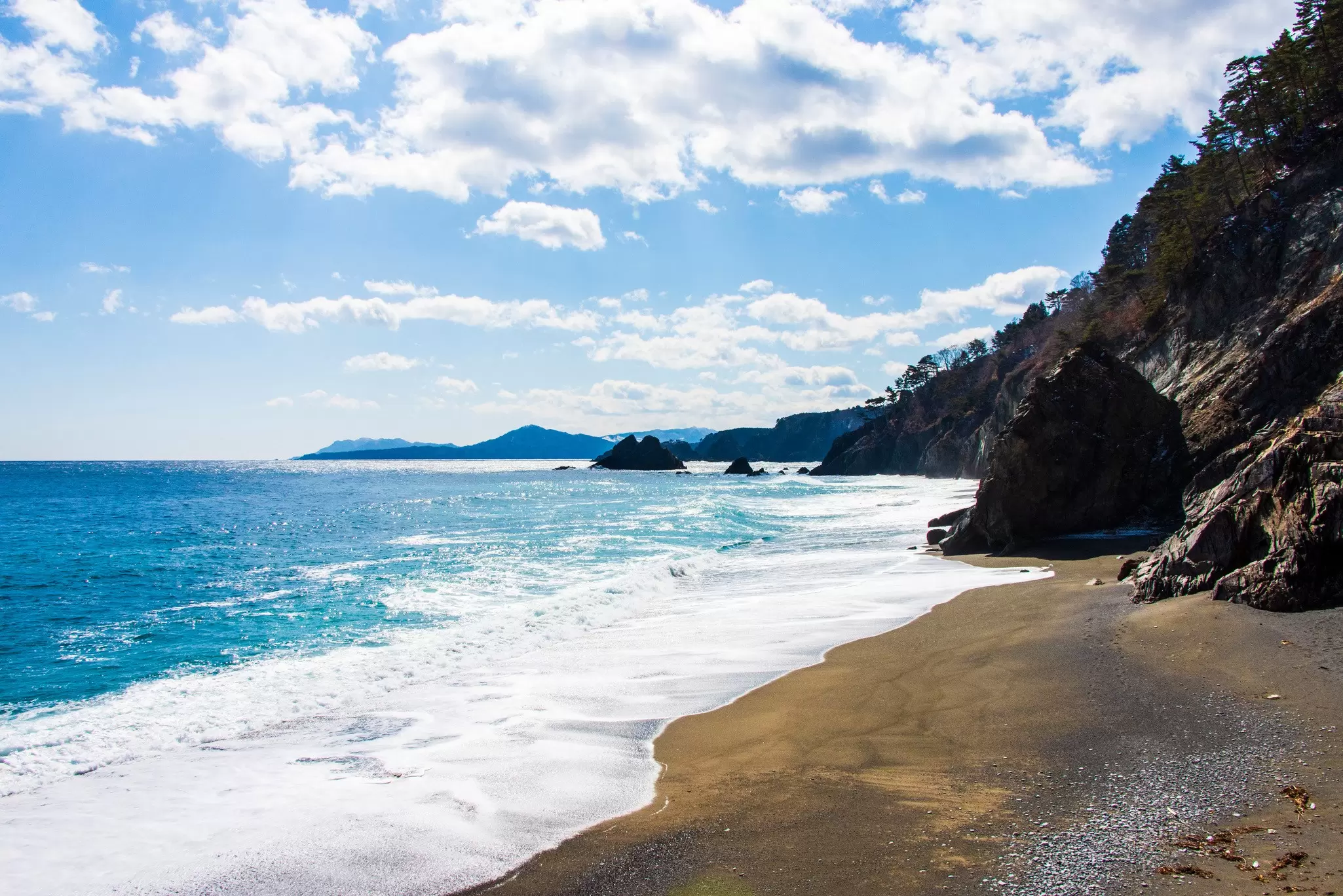  A beach with waves landing on sand and blue sky above in Taro, along the Michinoku Coastal Trail, Tohoku, Honshu, Japan.