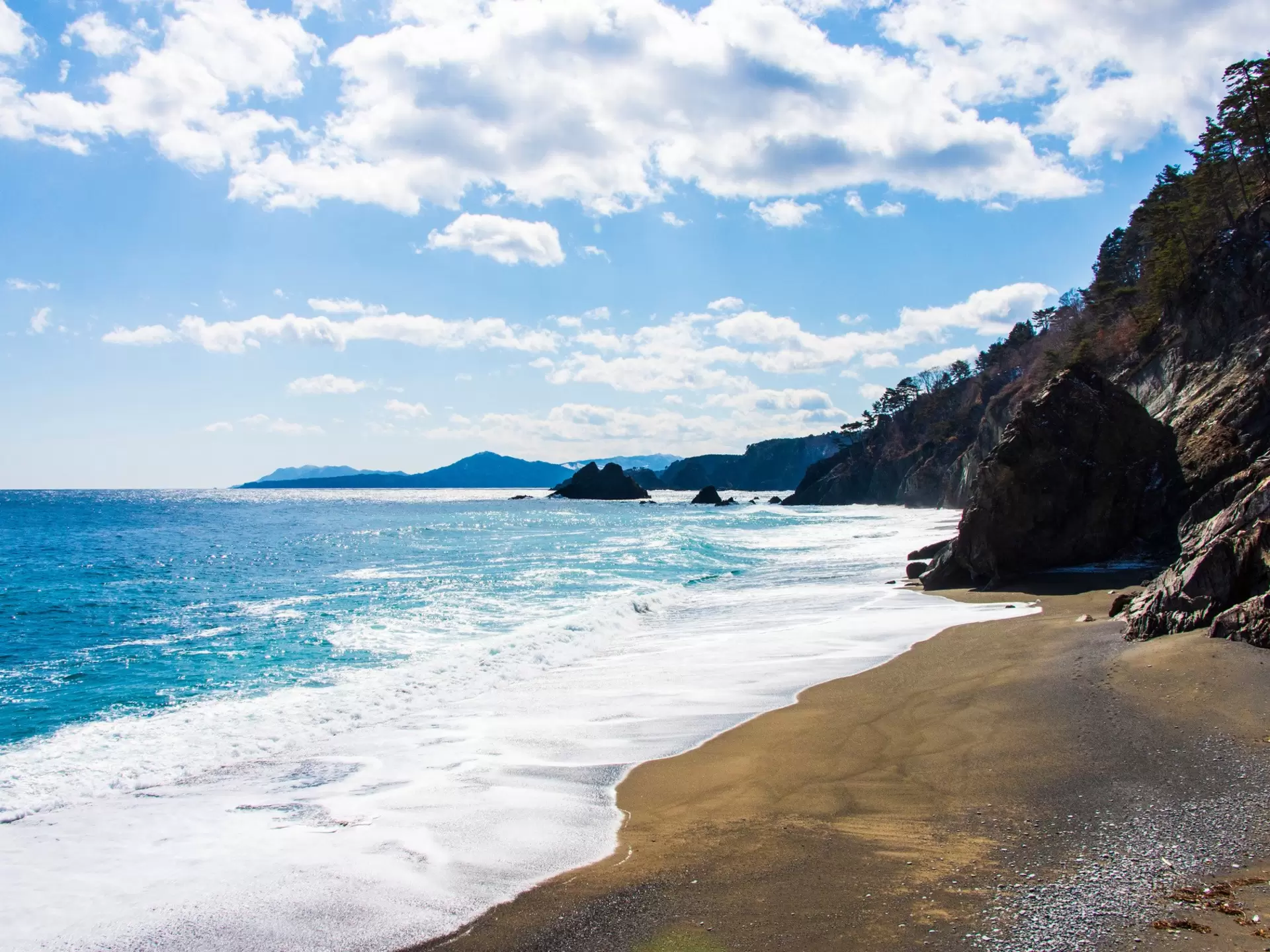  A beach with waves landing on sand and blue sky above in Taro, along the Michinoku Coastal Trail, Tohoku, Honshu, Japan.