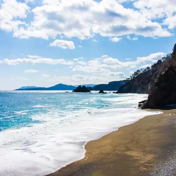  A beach with waves landing on sand and blue sky above in Taro, along the Michinoku Coastal Trail, Tohoku, Honshu, Japan.