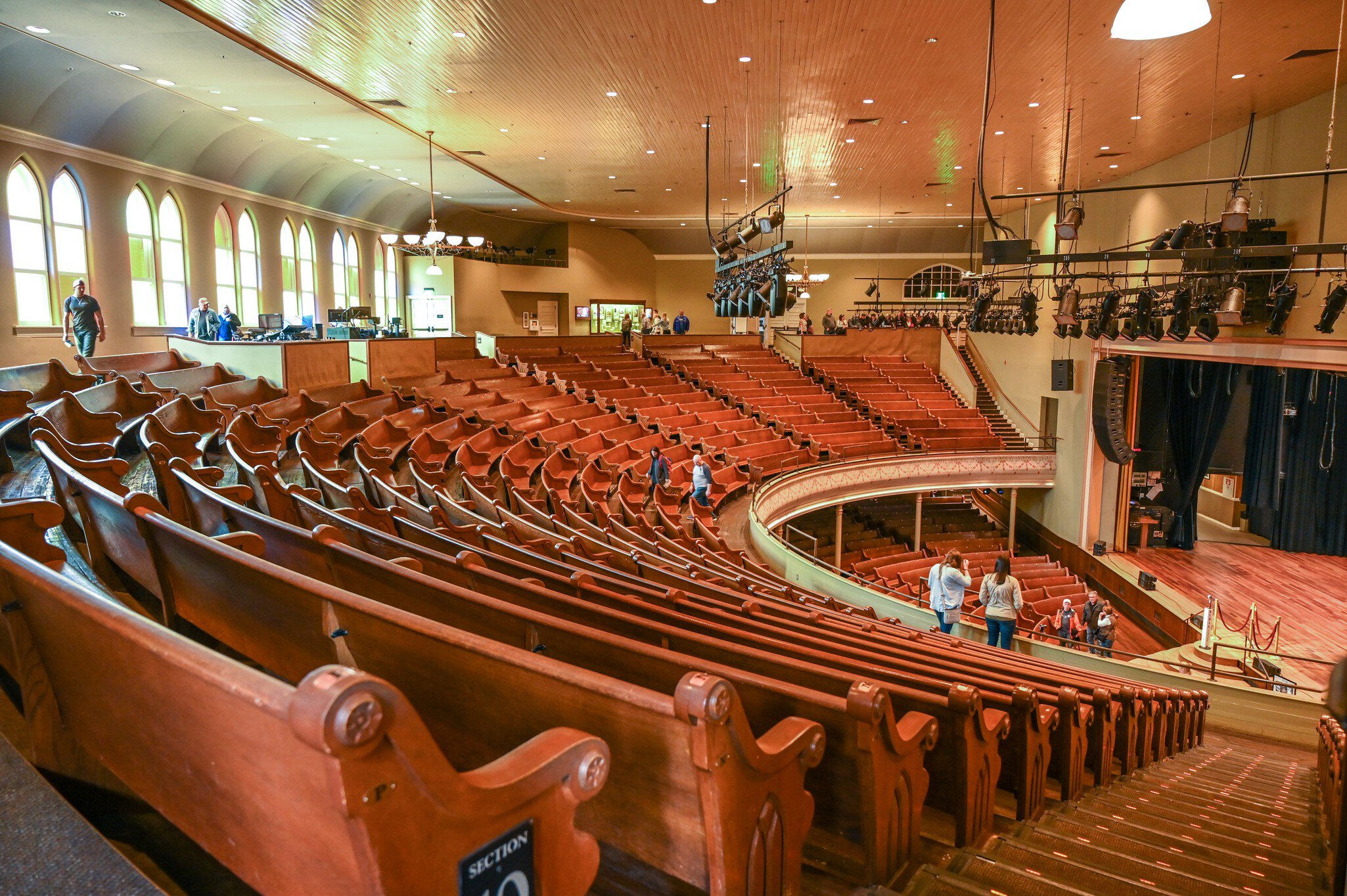 People stand among the wooden pews in the balcony of a former church