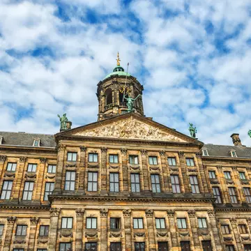 The Royal Palace in Amsterdam is situated in the west side of Dam Square in the centre of Amsterdam, Holland. Beautiful blue sky with cloudscape over the palace. The Netherlands.