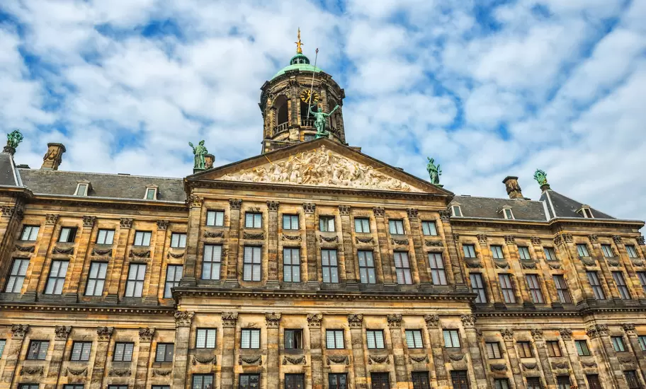 The Royal Palace in Amsterdam is situated in the west side of Dam Square in the centre of Amsterdam, Holland. Beautiful blue sky with cloudscape over the palace. The Netherlands.