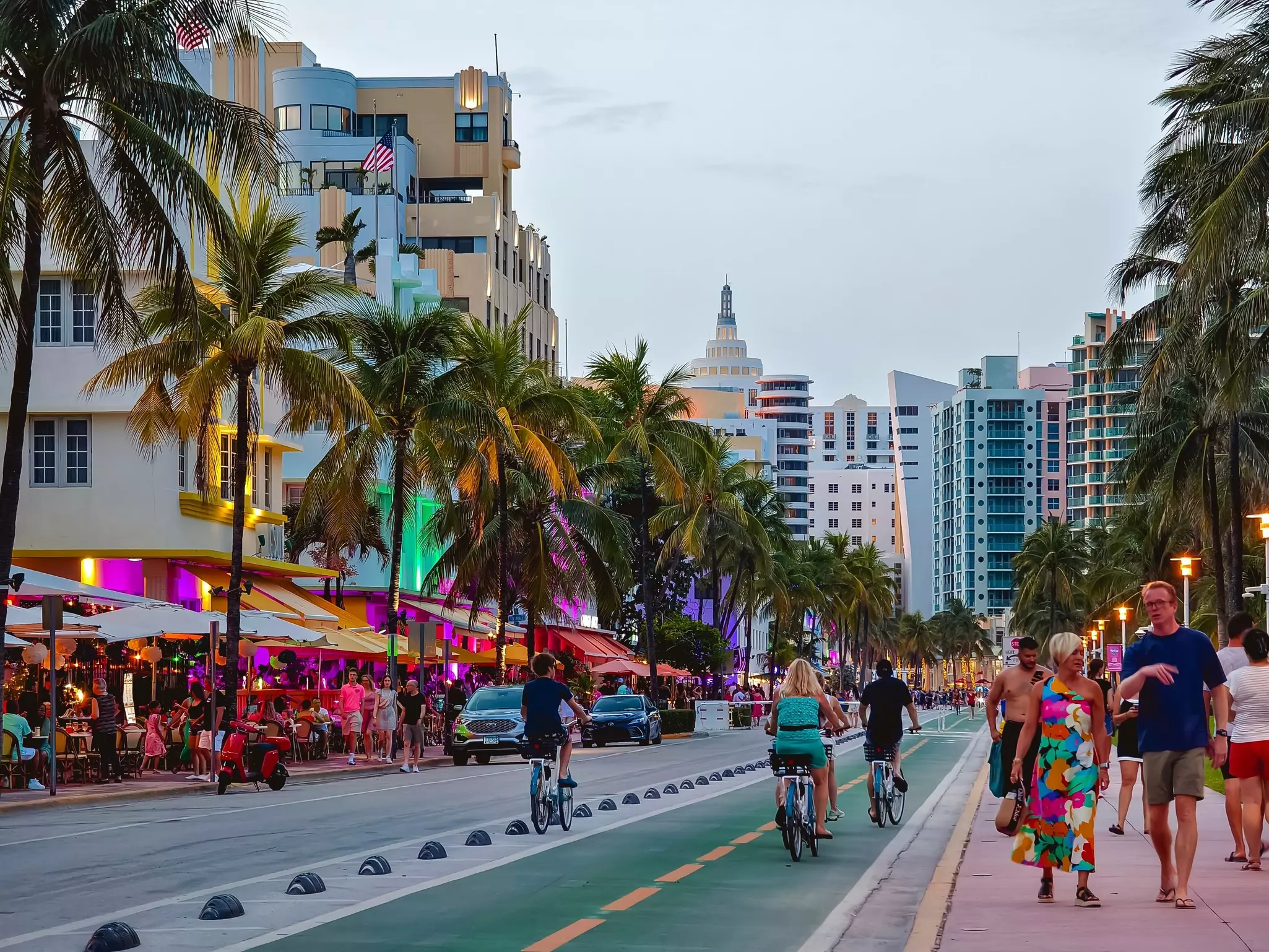 People enjoying a vibrant evening at Ocean Drive in South Beach, Miami, with colorful buildings, palm trees, and lively atmosphere.