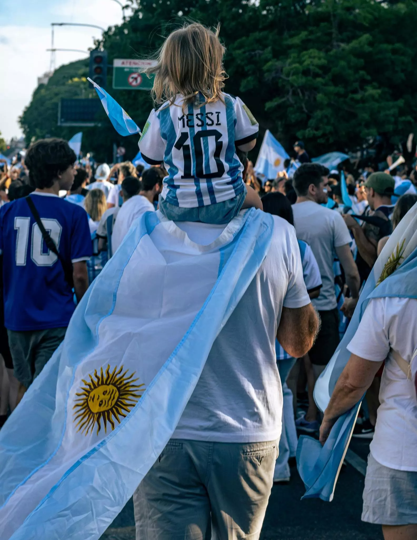 A Child being carried on her Father's shoulders in march of Argentina Football Fans at the 2022 World Cup in Buenos Aires, Argentina