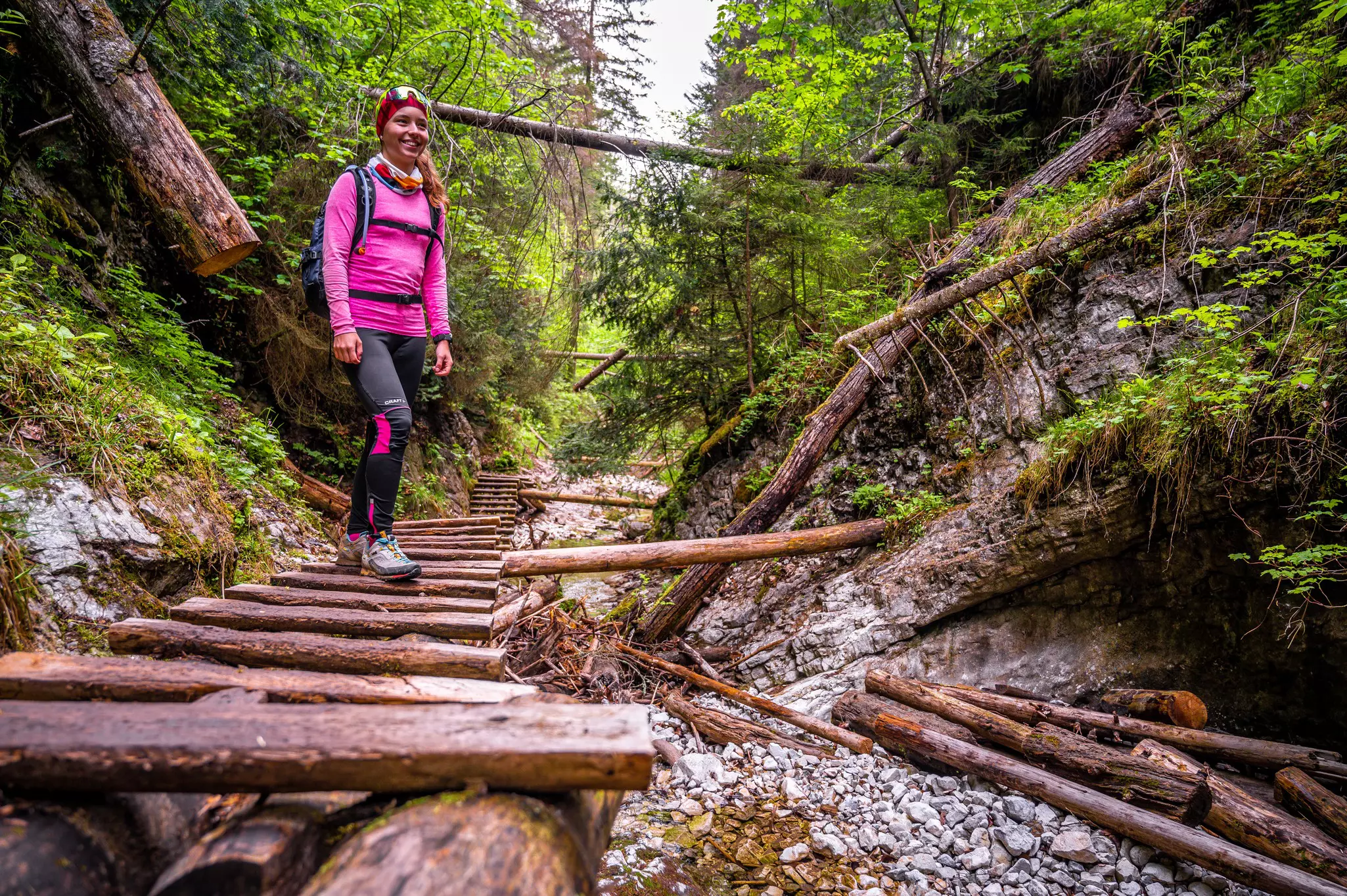 A woman on a ladder walkway by a waterfall at Slovensky Raj National Park, Slovakia