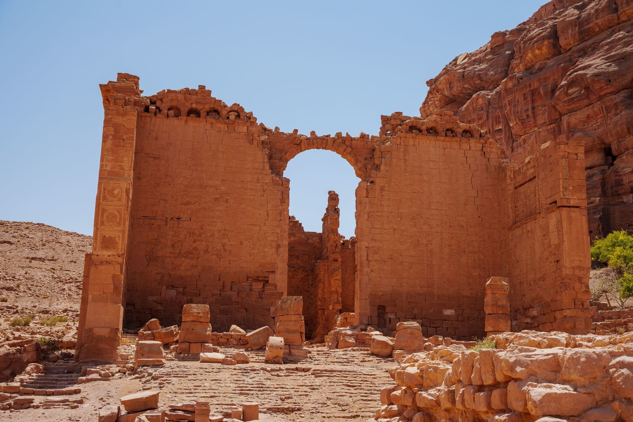The ruins of the Qasr al-Bint temple in Petra against a blue sky