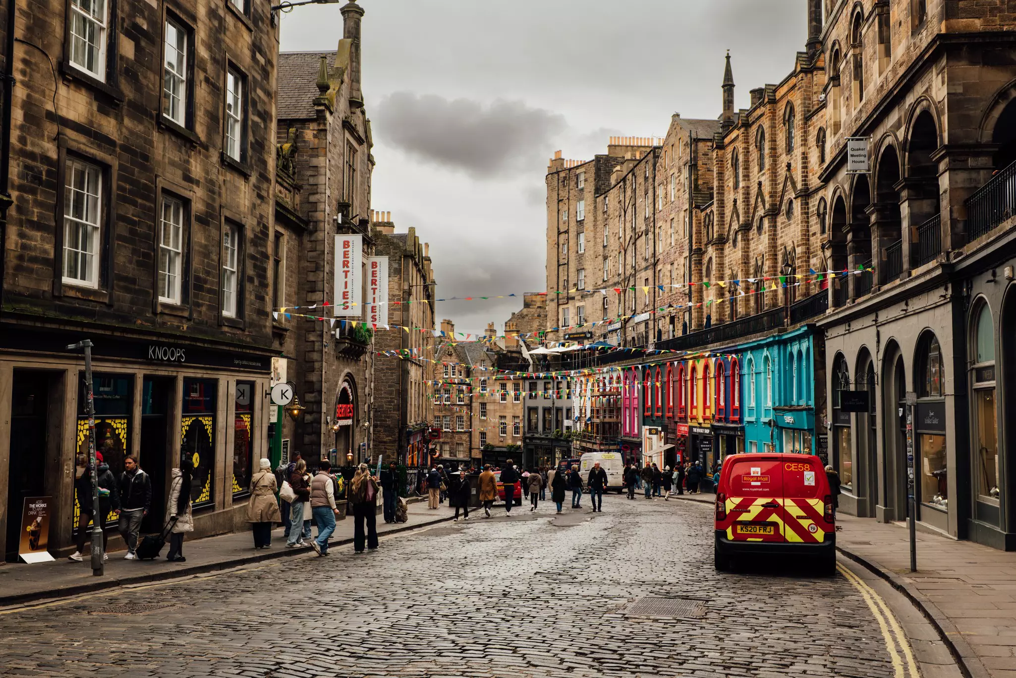 People walking along a cobbled street after rain in Edinburgh, Scotland.