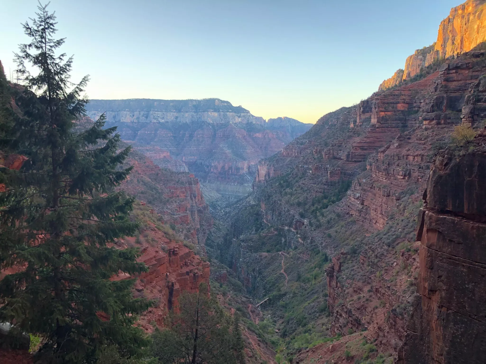 The stripes on rocks within a vast canyon light up as the sun rises.