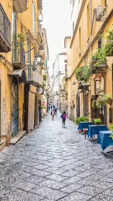A narrow, mostly empty street with yellow historic buildings on either side.