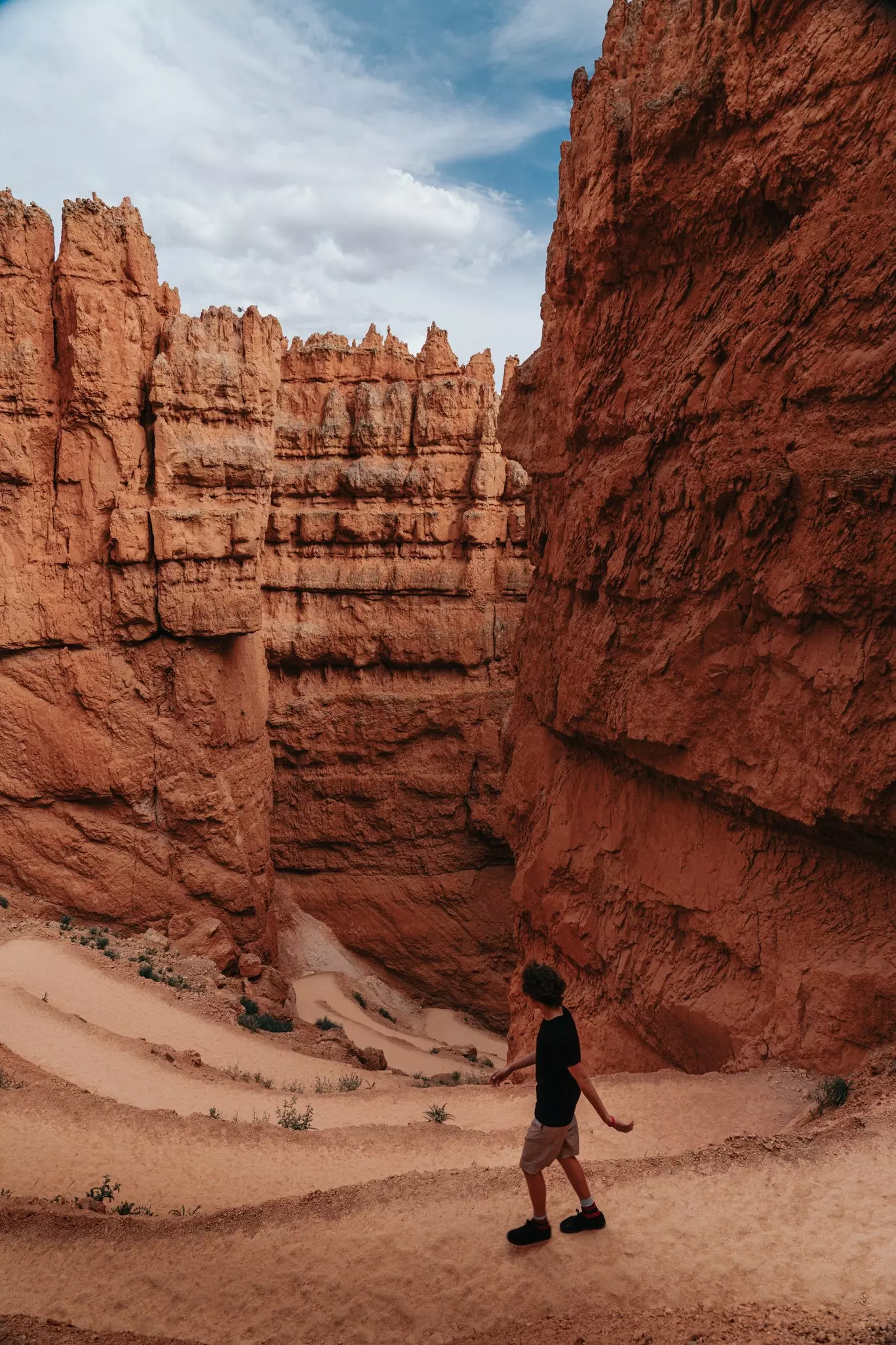 Hiker Walking Down Winding Queen's Trail Between Bryce Canyon Walls