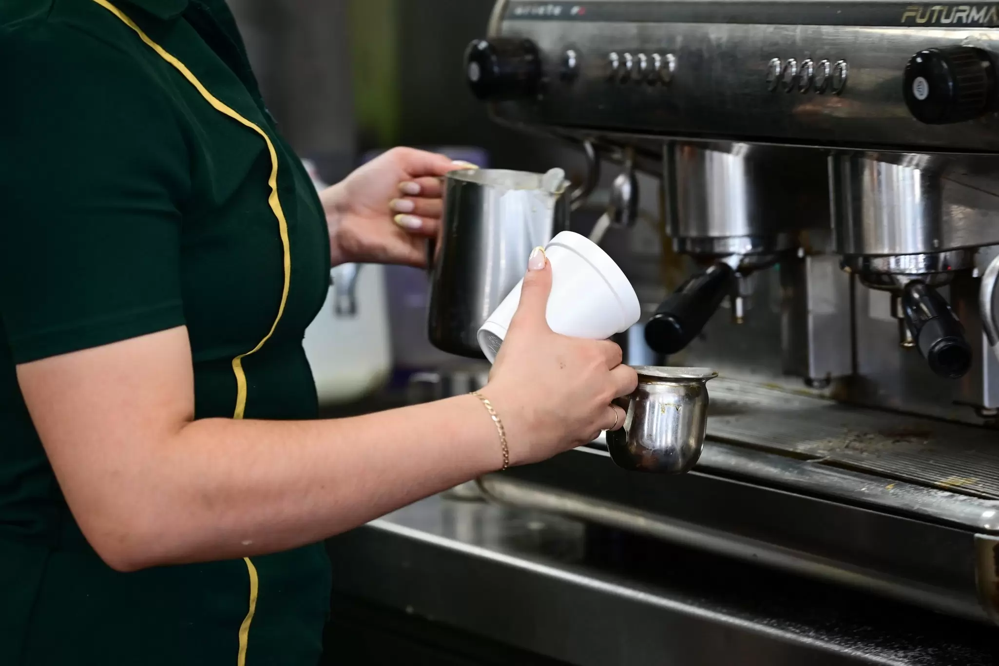 close-up of a barista standing at a coffee machine preparing a drink