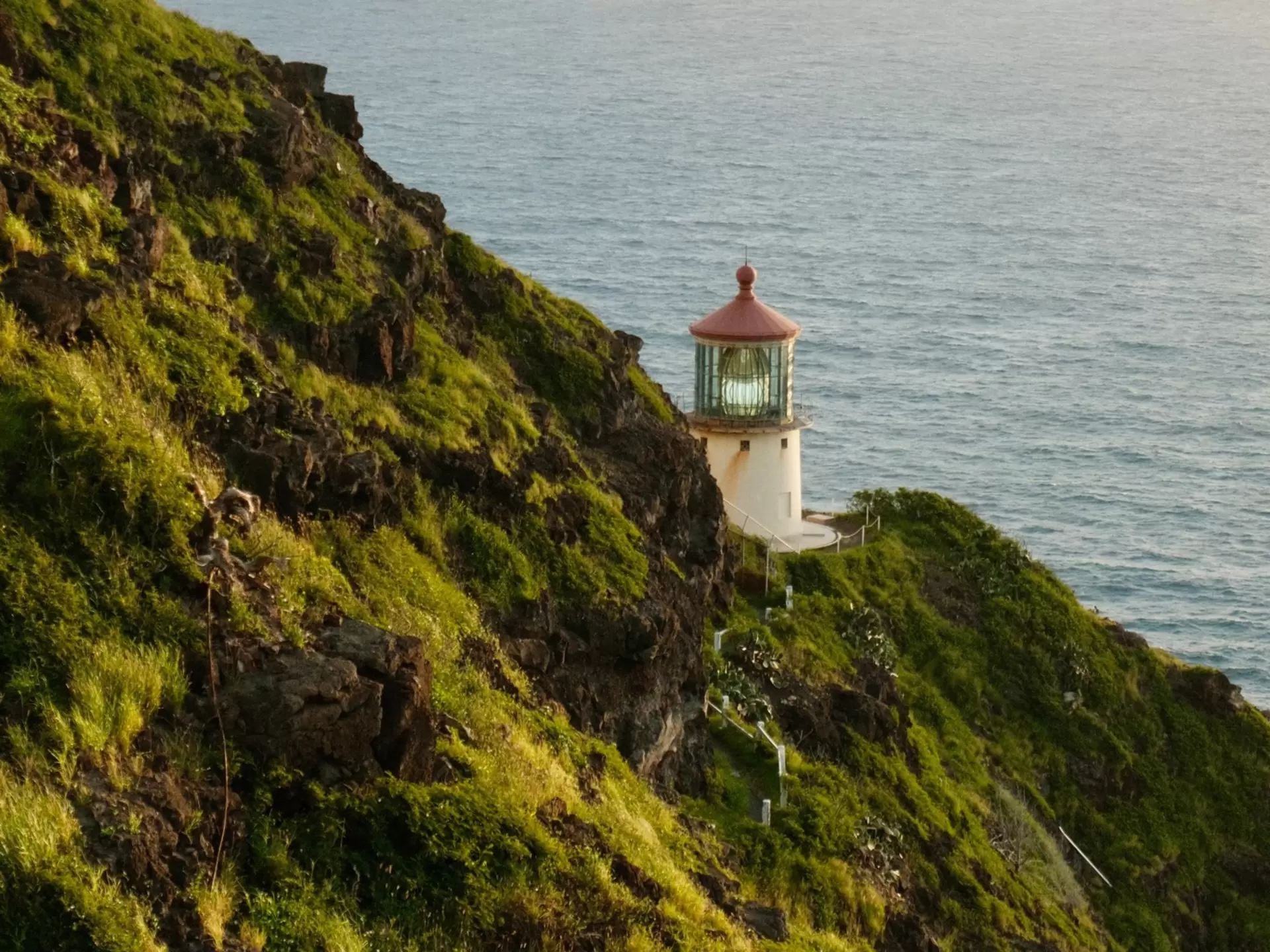 A small lighthouse tucked into the folds of a coastal path: Makapuʻu Lighthouse on Oʻahu, Hawaii