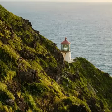 A small lighthouse tucked into the folds of a coastal path: Makapuʻu Lighthouse on Oʻahu, Hawaii