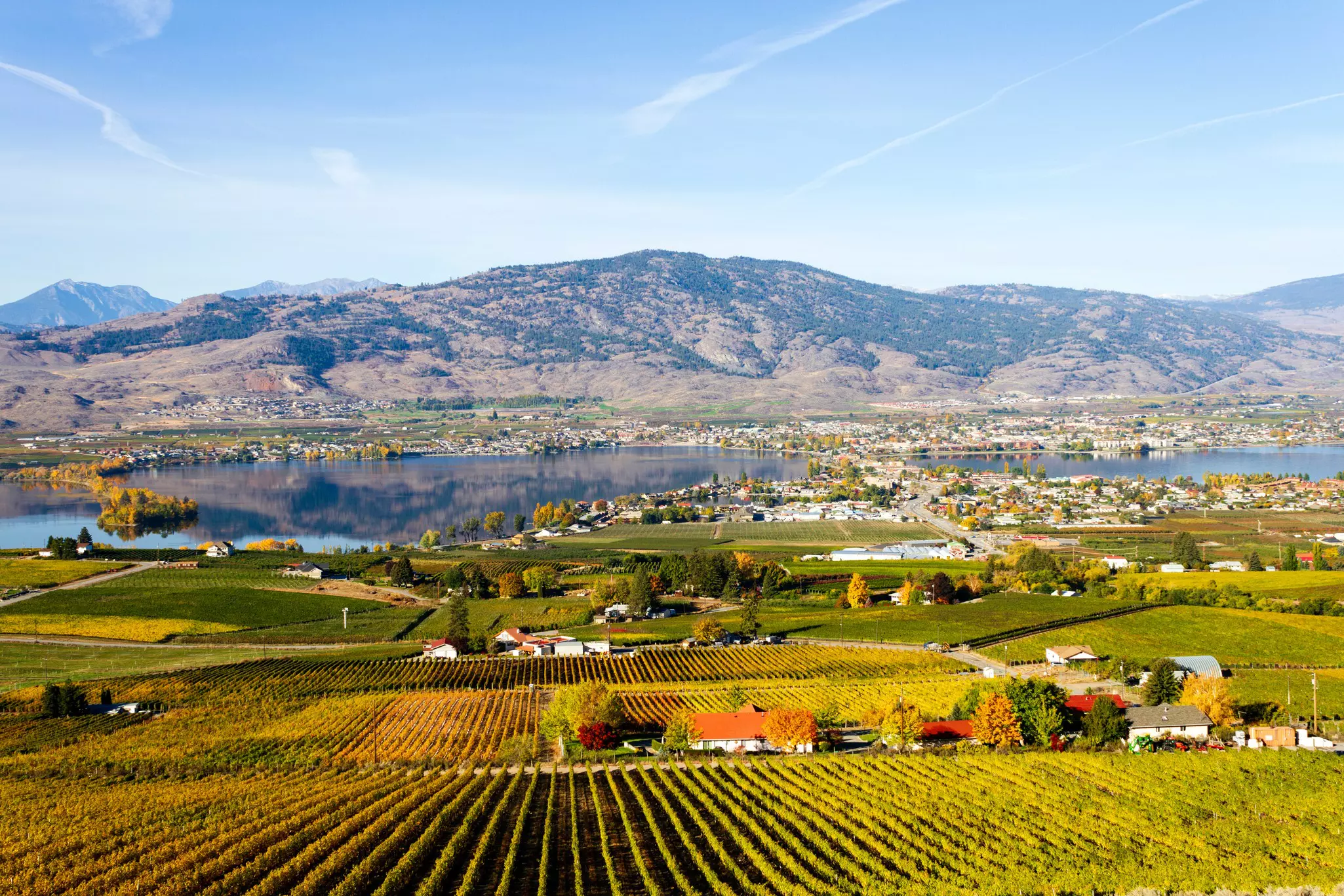 small town surrounding a lake with farms in the foreground and a rising hill in the background.