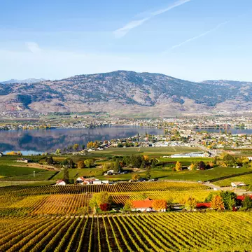 small town surrounding a lake with farms in the foreground and a rising hill in the background.