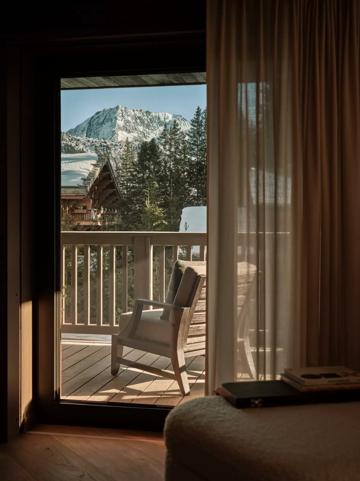 A chair on a balcony with views over a nearby snow-capped mountain: Rosewood Courchevel 