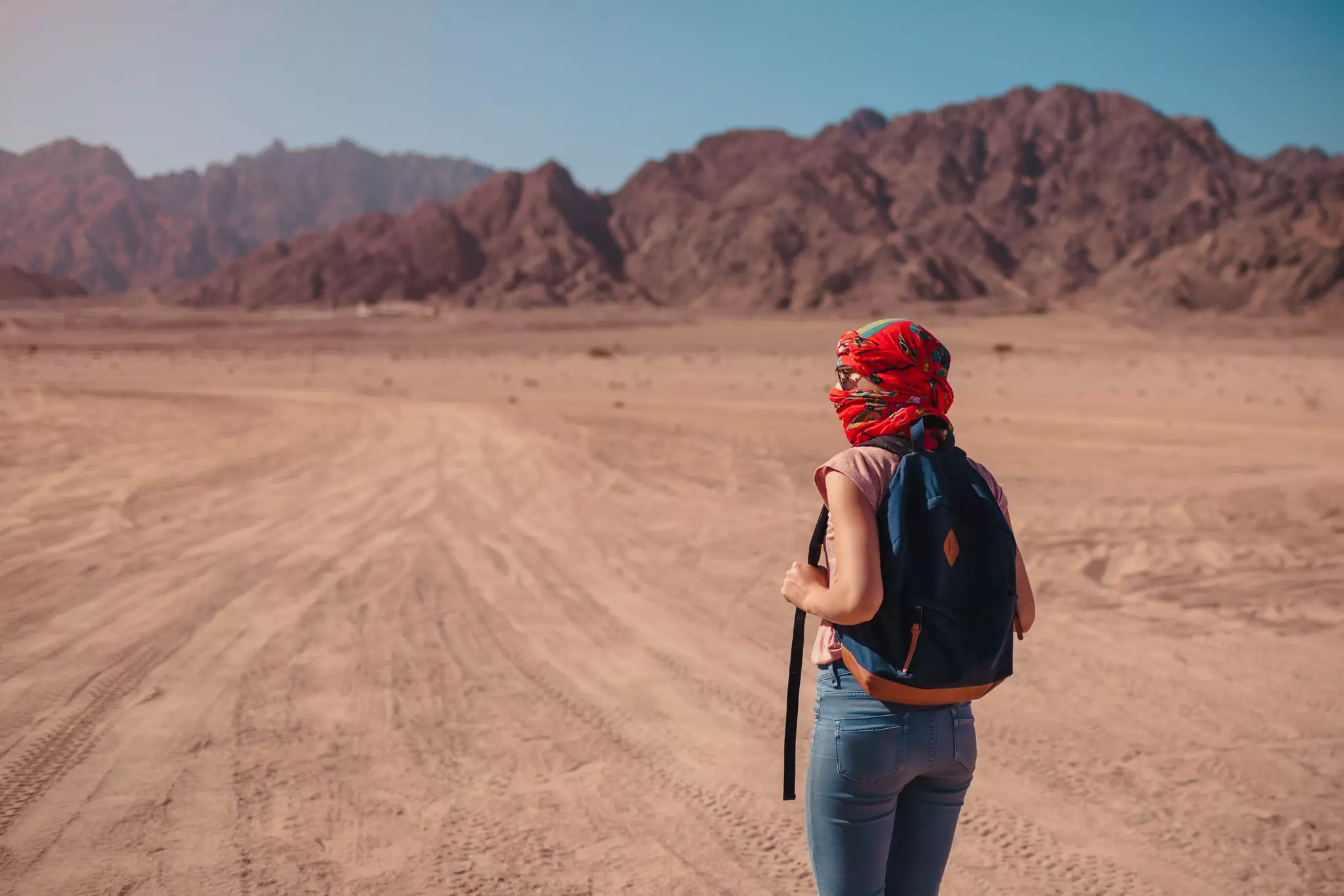Tourist woman with backpack wearing scarf on head in the Sinai Desert, Egypt
