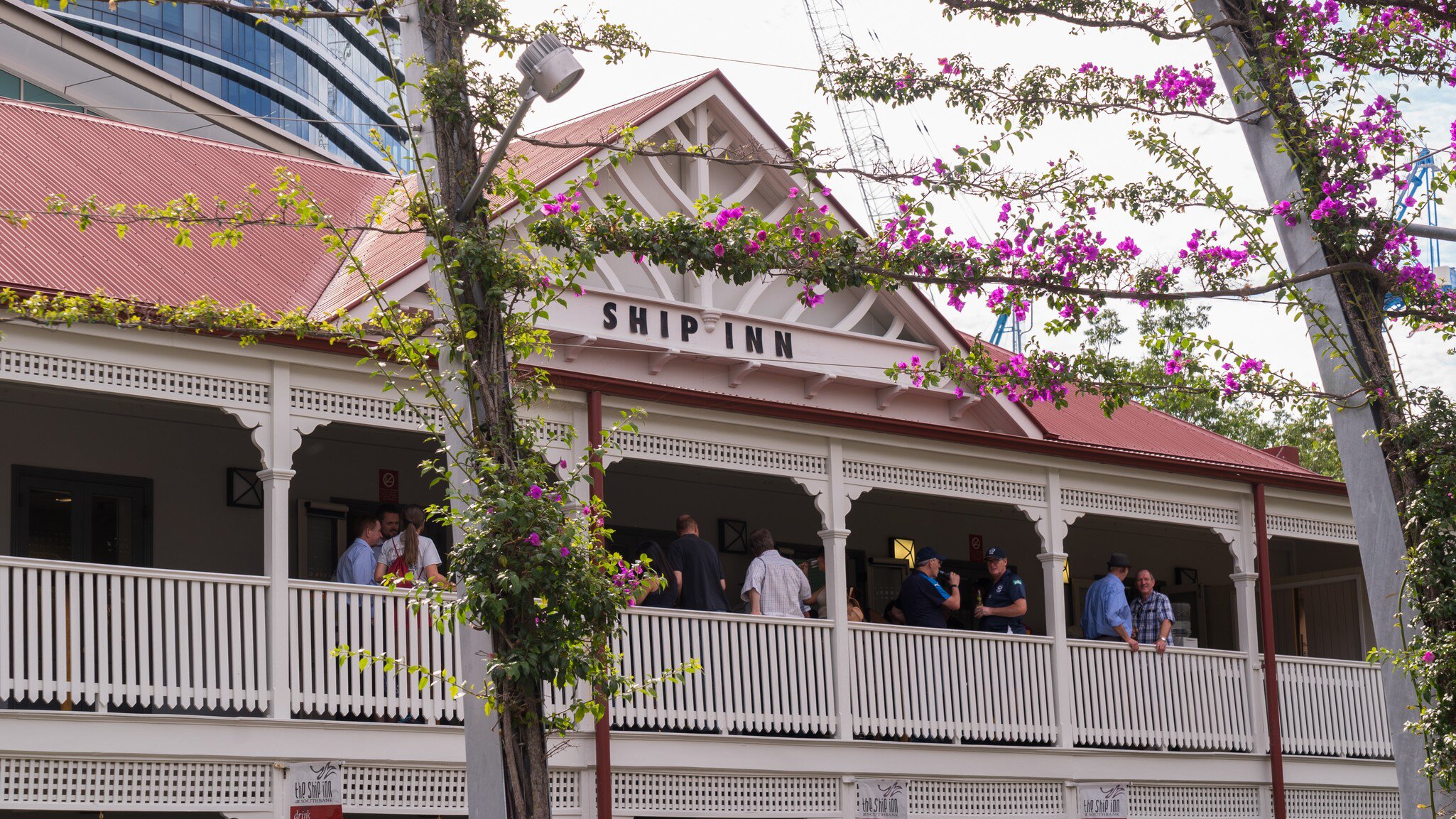Facade of The Ship Inn in Brisbane, Australia, surrounded by pink flowers.