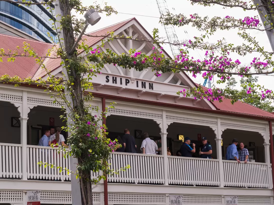 Facade of The Ship Inn in Brisbane, Australia, surrounded by pink flowers.