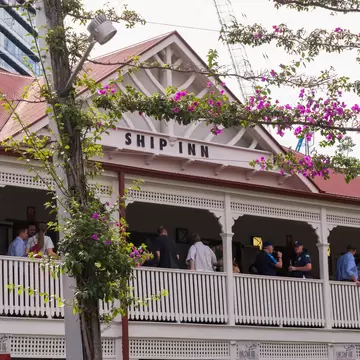 Facade of The Ship Inn in Brisbane, Australia, surrounded by pink flowers.