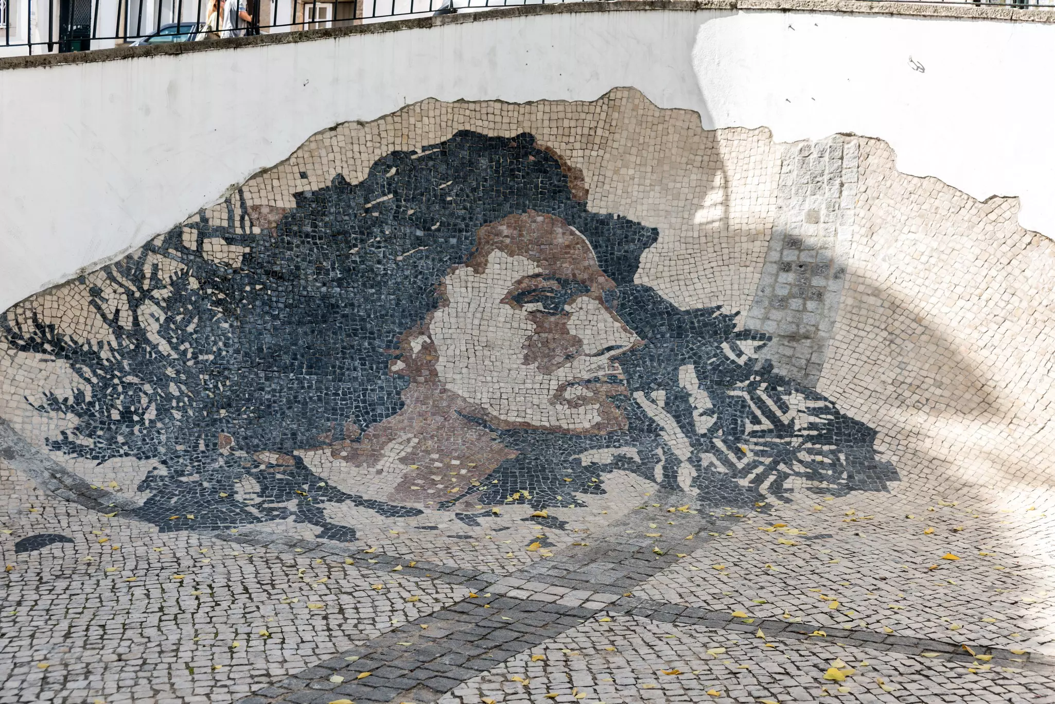 A portrait of a woman created in black and white tiles and set in the sidewalk.