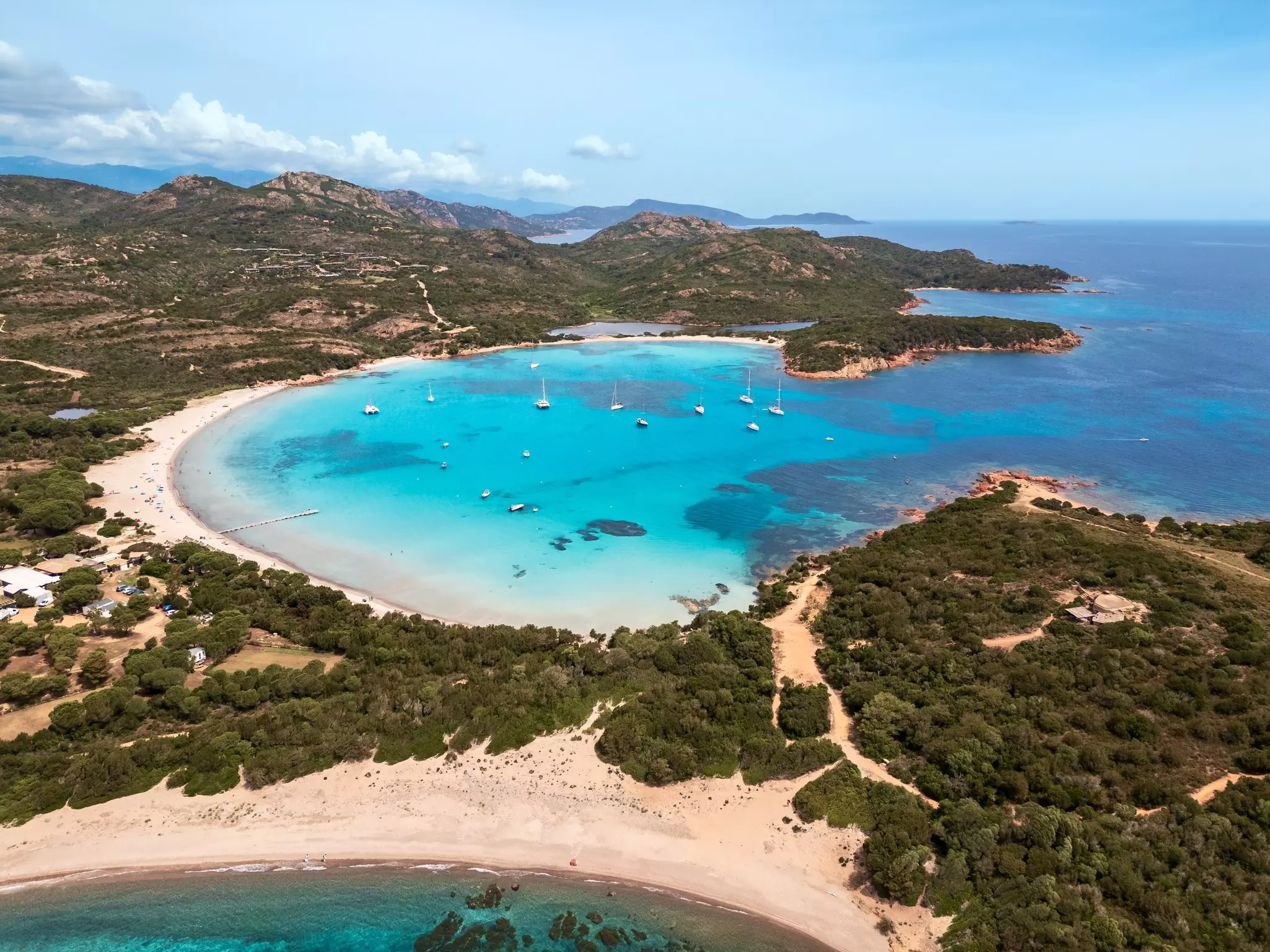 Aerial view of yachts moored in the turquoise Mediterranean sea at the bay of Rondinara on the island of Corsica. 