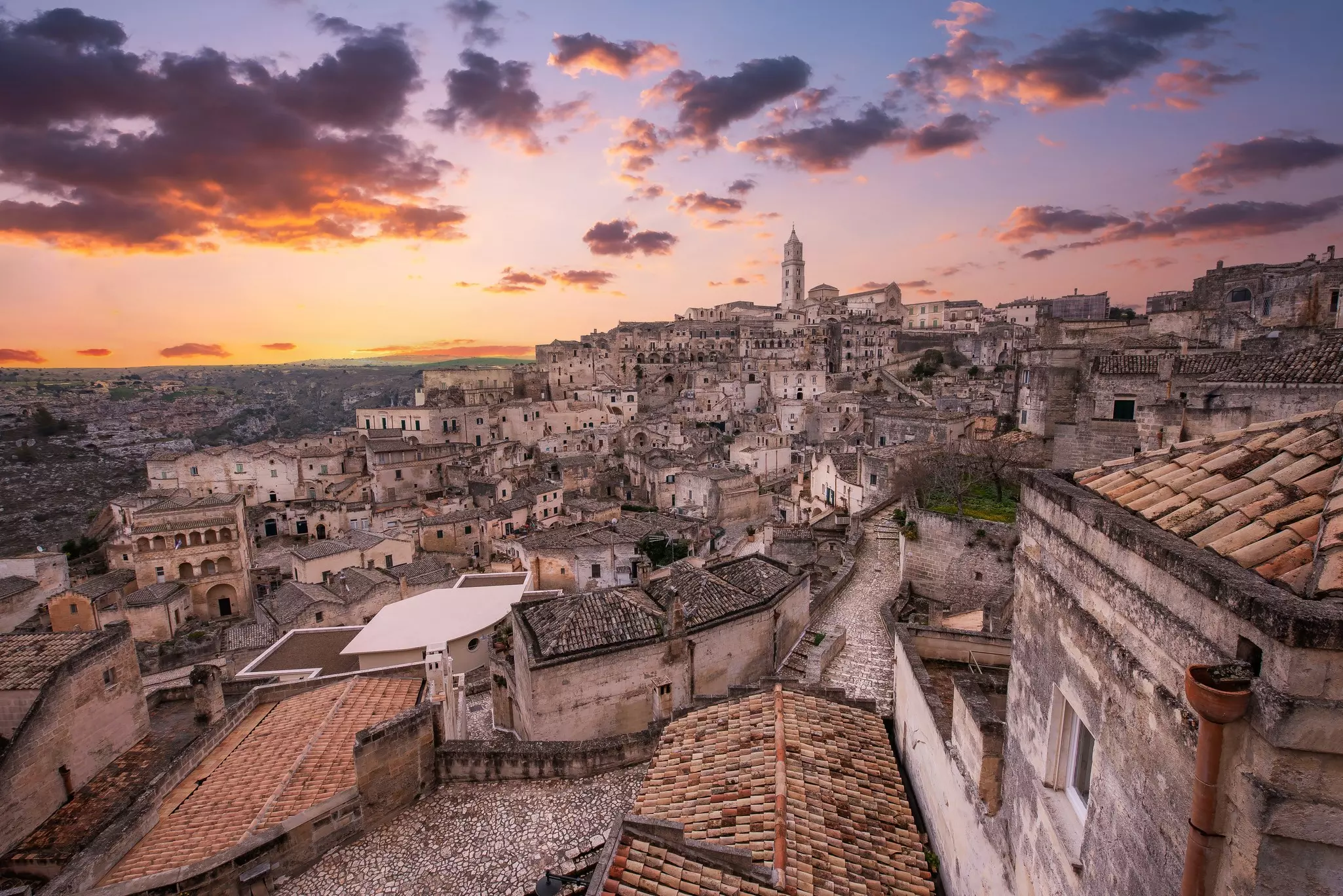 Sunset over an atmospheric hilltop town with lots of small ancient dwellings tucked into the hillside.