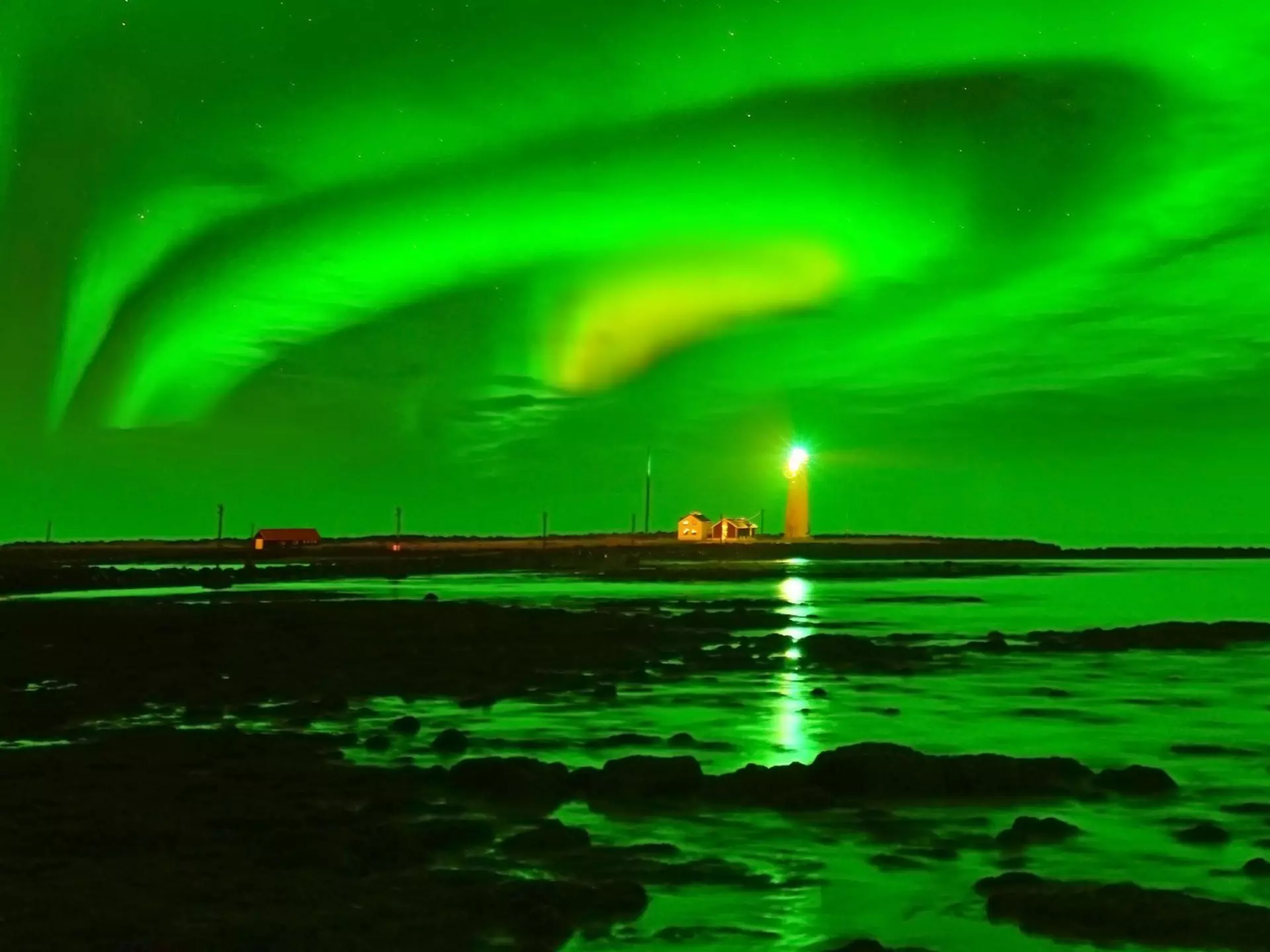 A glowing green sky over a lighthouse