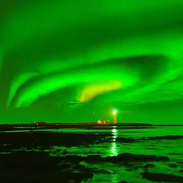 A glowing green sky over a lighthouse