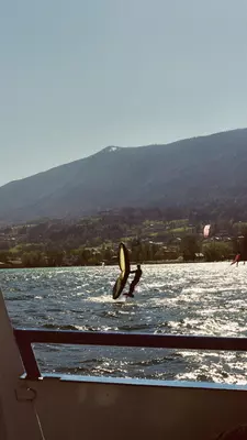 A windsurfer passes a boat on a lake