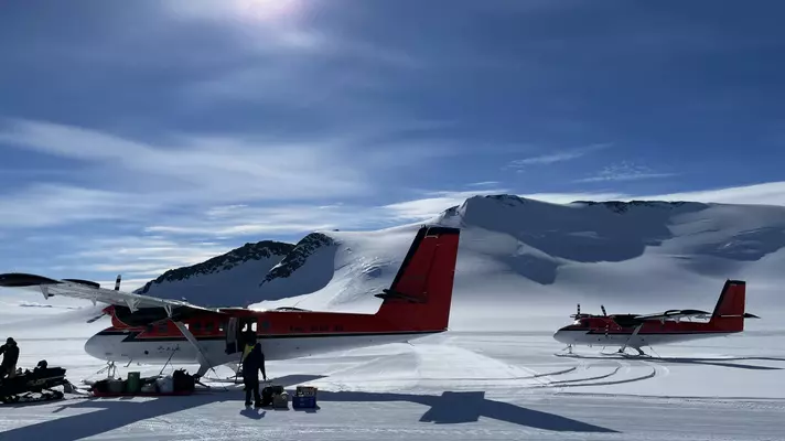 Two small planes on a snow-covered surface.