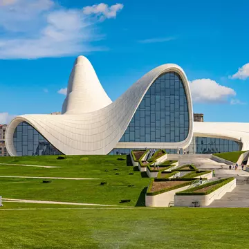 Exterior of modern cultural center in Baku, the capital of Azerbaijan. Blue sky and green lawn below.
