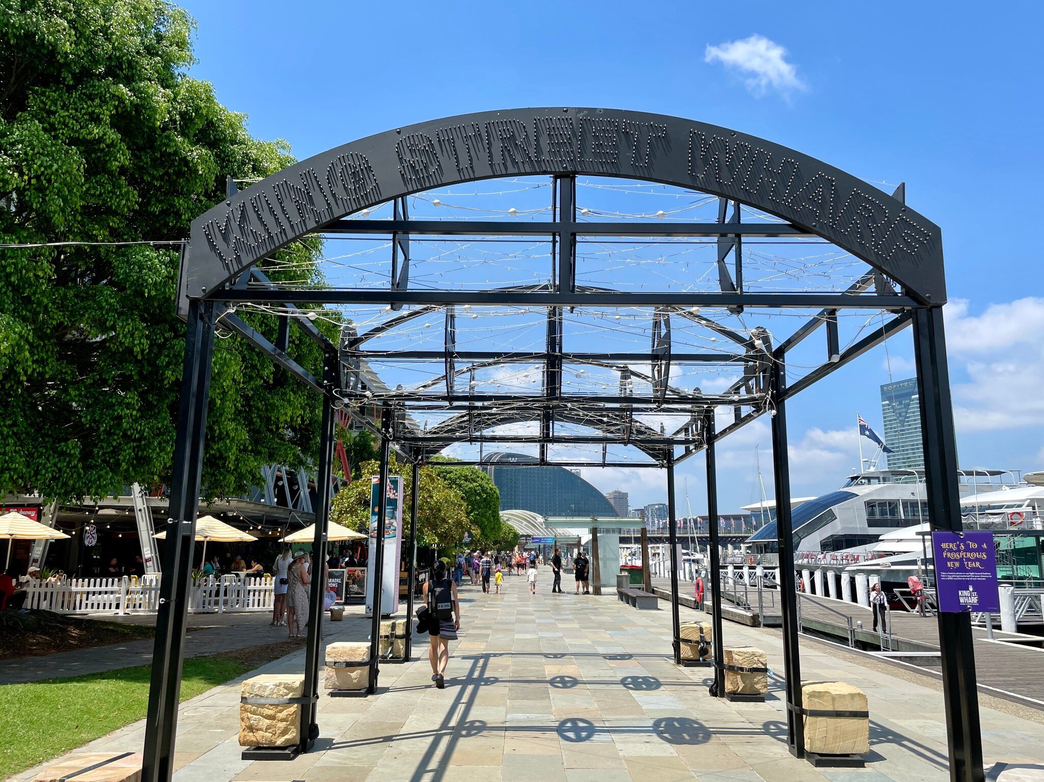 King Street Wharf Promenade in Darling Harbour. People walking along promenade and tourists and locals waiting to take a  cruise around the harbour. Sydney, Australia.