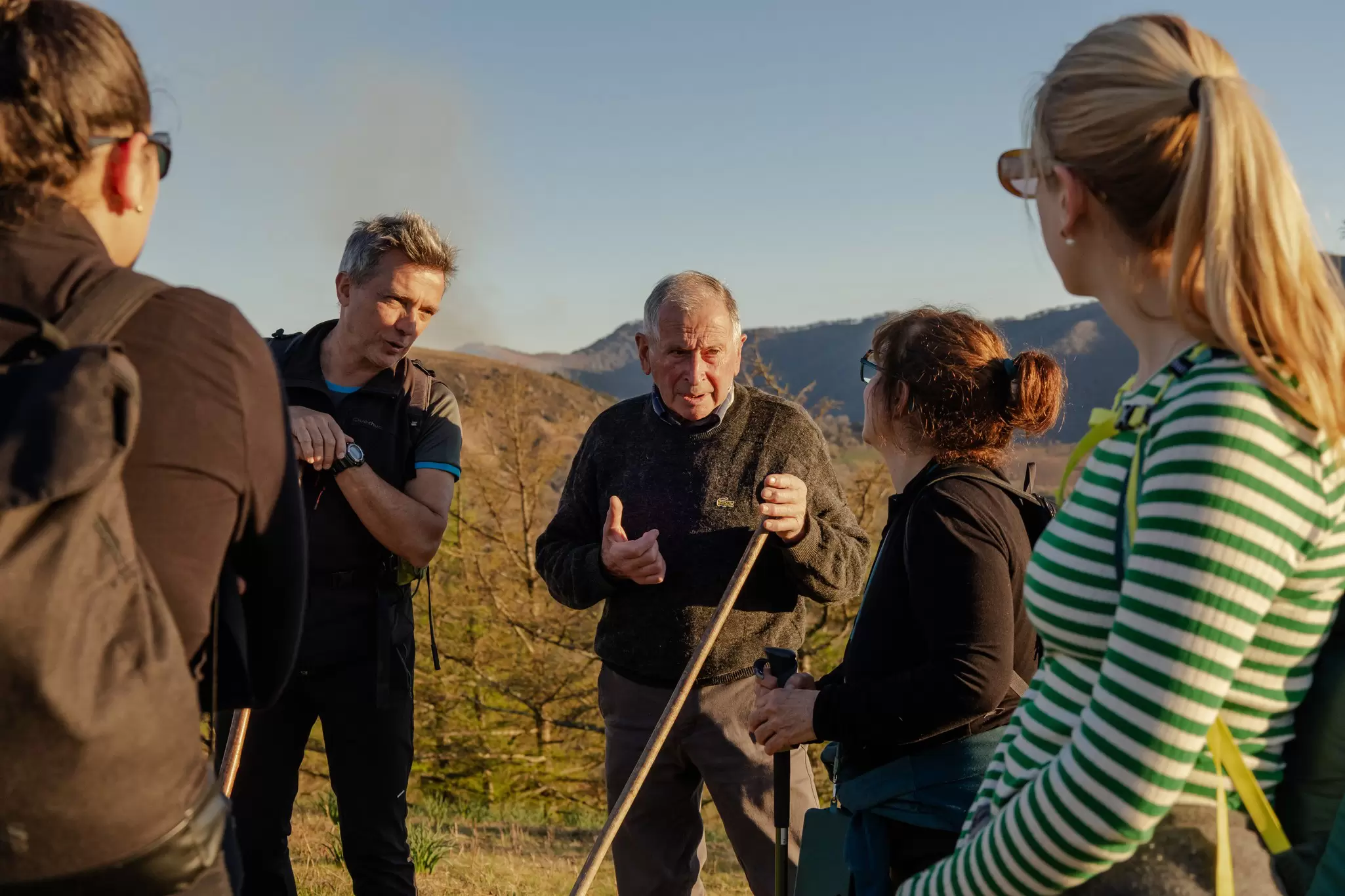 A group of hikers pause on the trail to listen to a guide tell a story about their route.