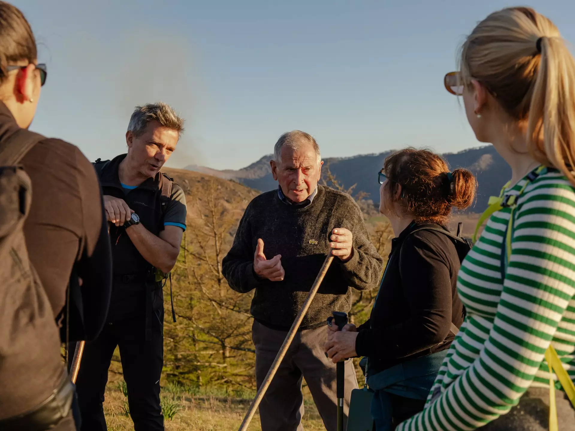 A group of hikers pause on the trail to listen to a guide tell a story about their route.