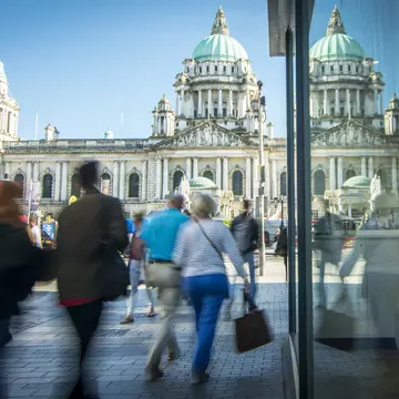 Motion blurred shoppers in front of Belfast city hall in Northern Ireland. William Barton / Getty Images
