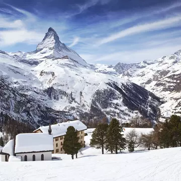 The Matterhorn rises over snowy rooftops near Zermatt in Switzerland.
