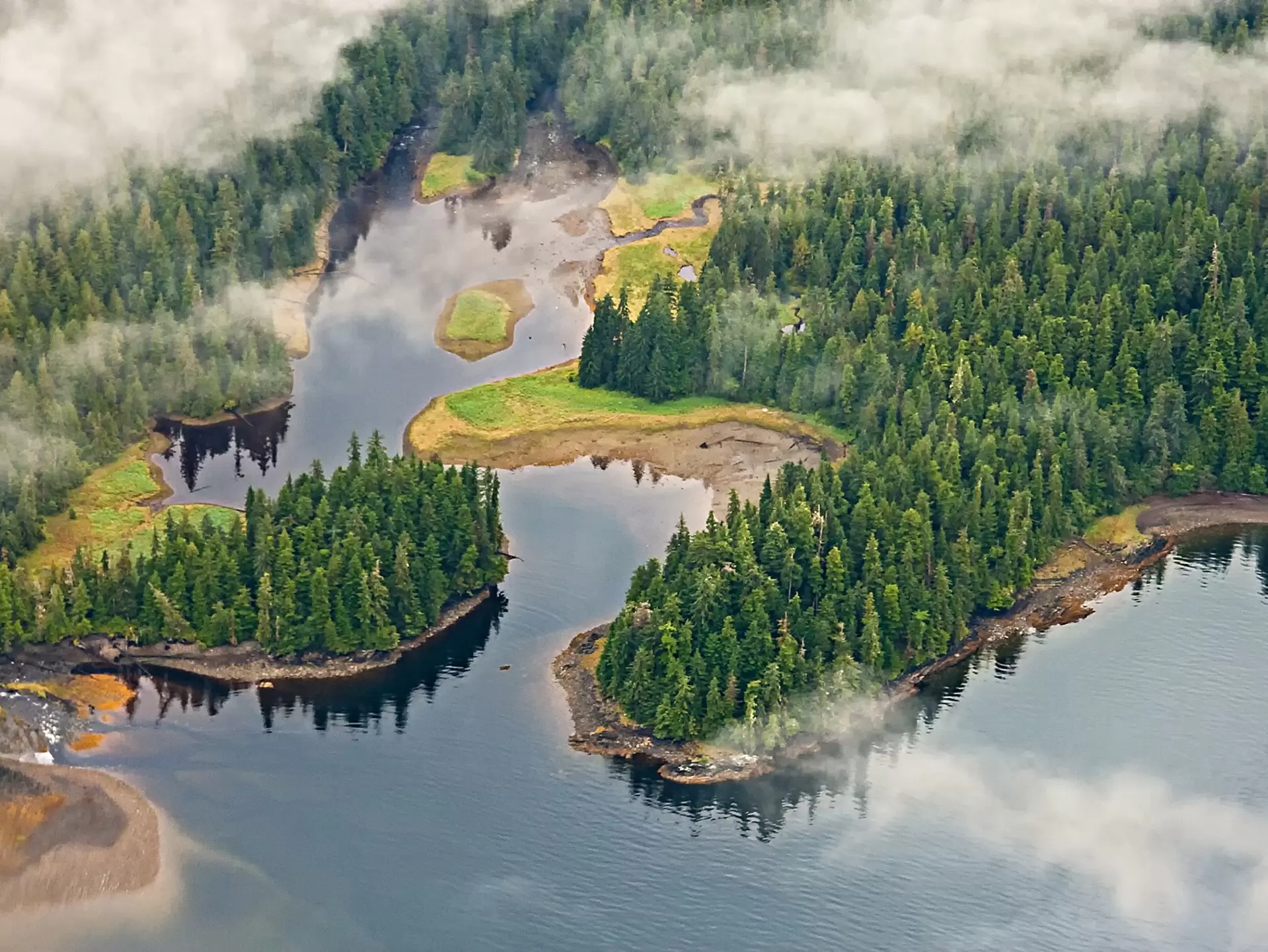 Aerial view of mist hovering around lakes, forest and mountains in a national park in Alaska.