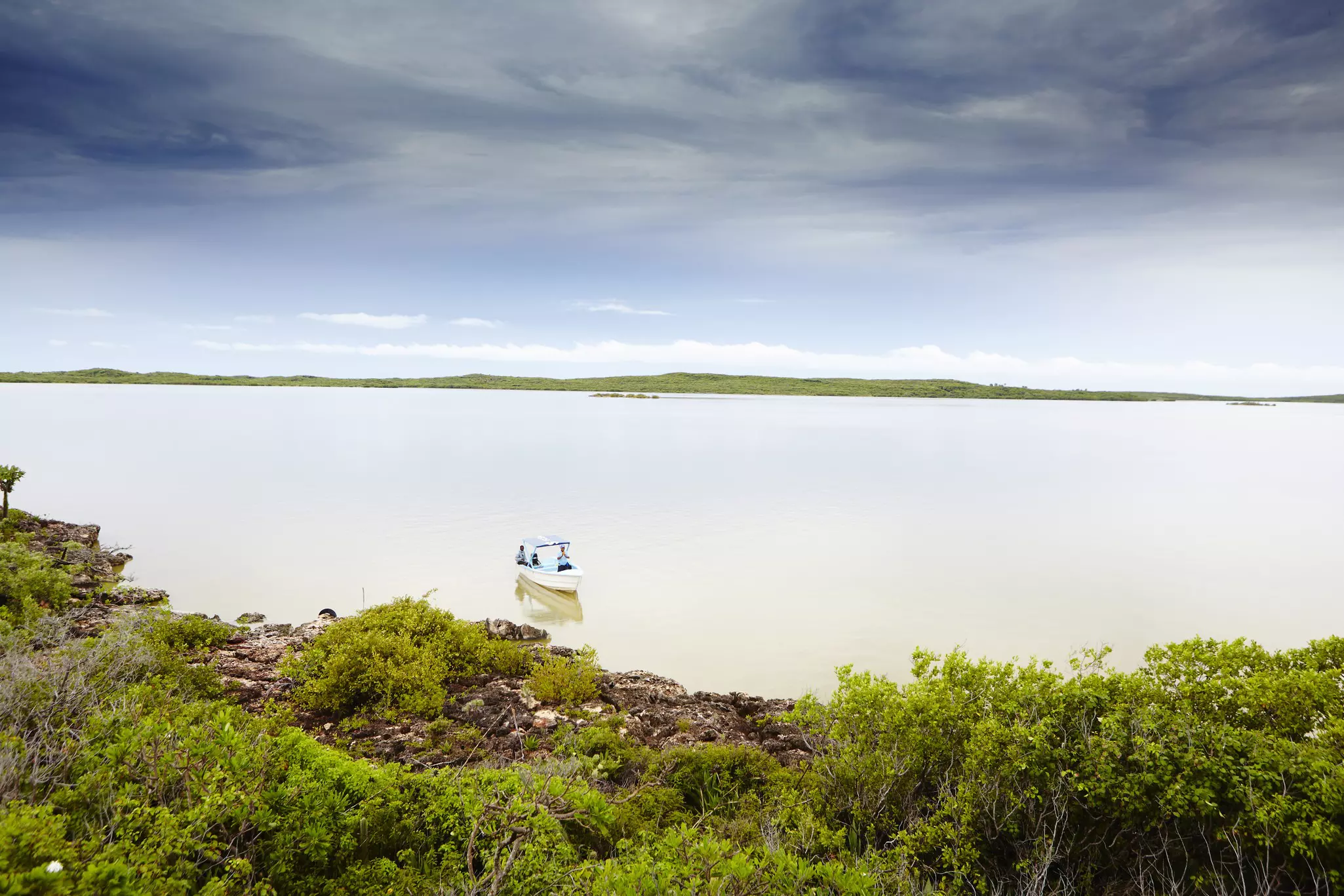 A boat in a lagoon with white cloud and blue sky above