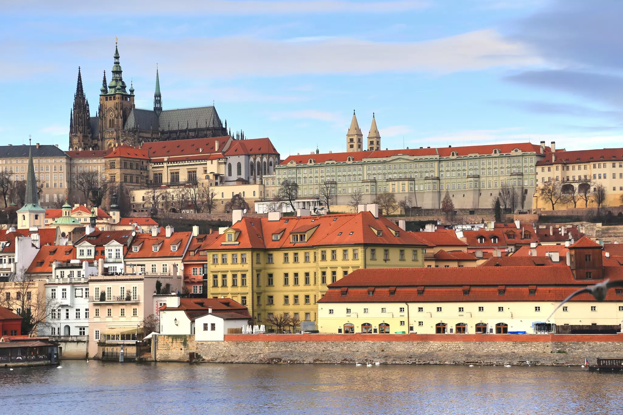 A castle structure on a hillside over a historic city by a river.