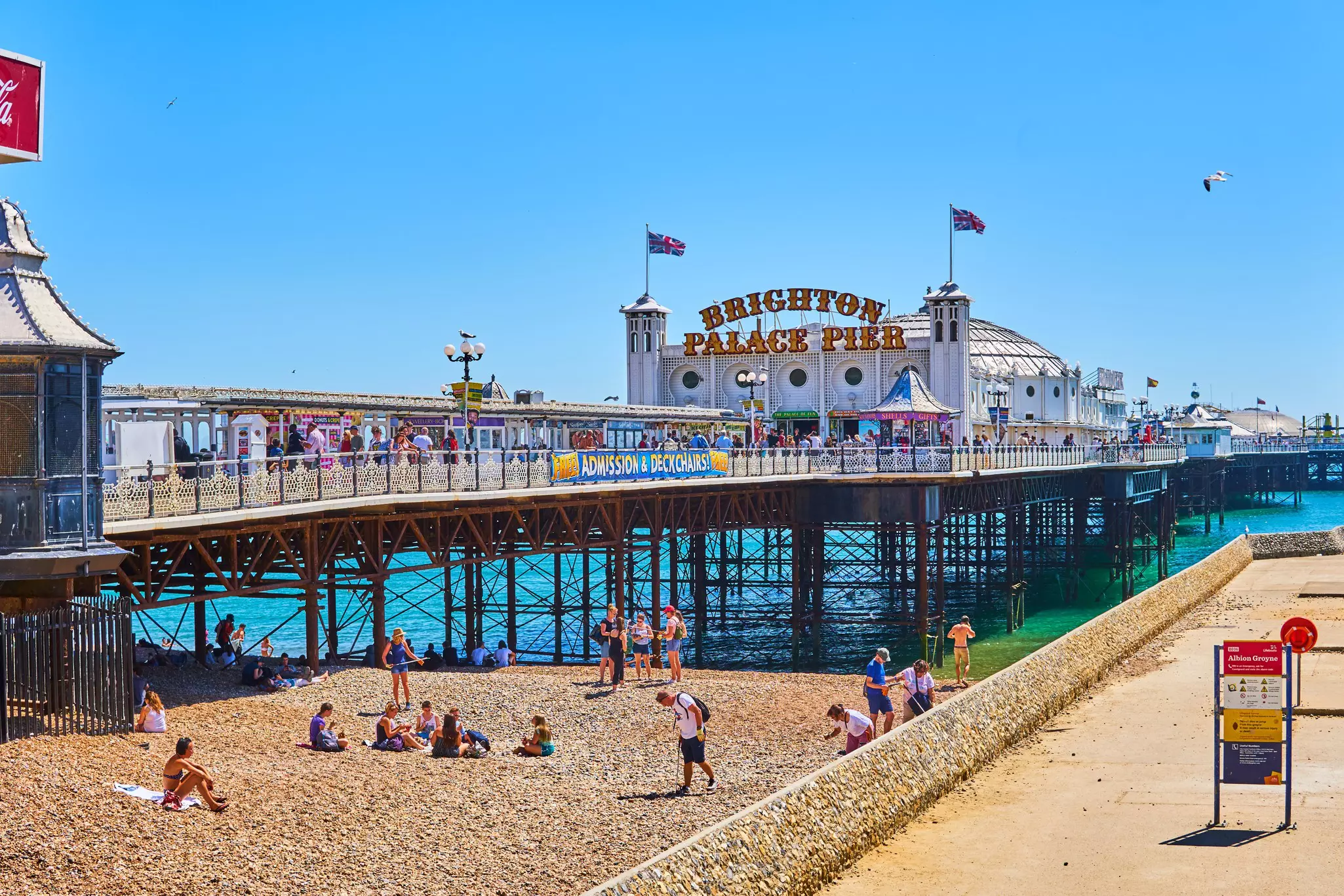 Brighton beach pier on a summers day with sunbathers and holiday makers, East Sussex, England
