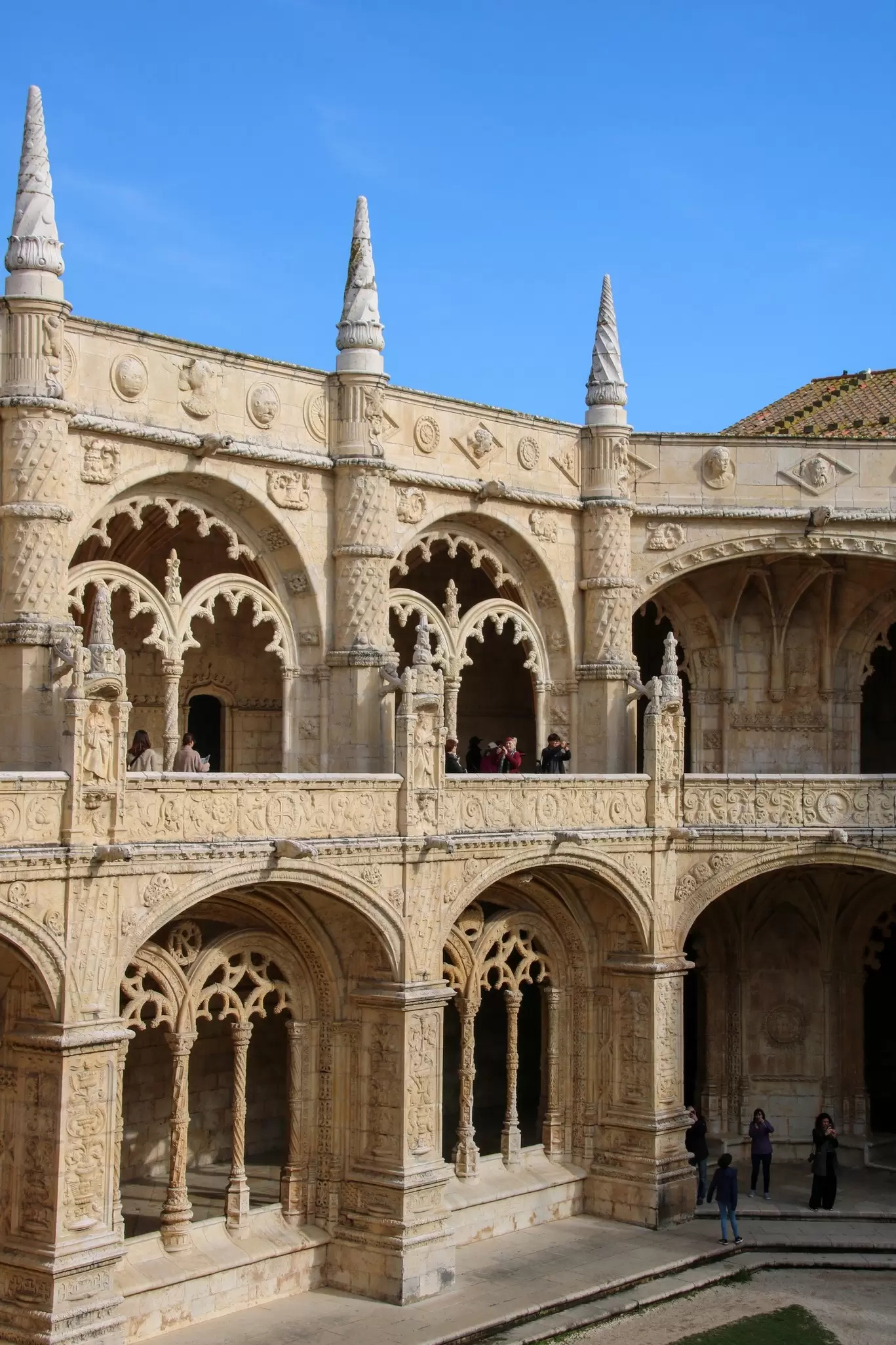 Tourists walking throughout the interior of the Mosteiro dos Jerónimos de Santa Maria de Belém in Lisbon.