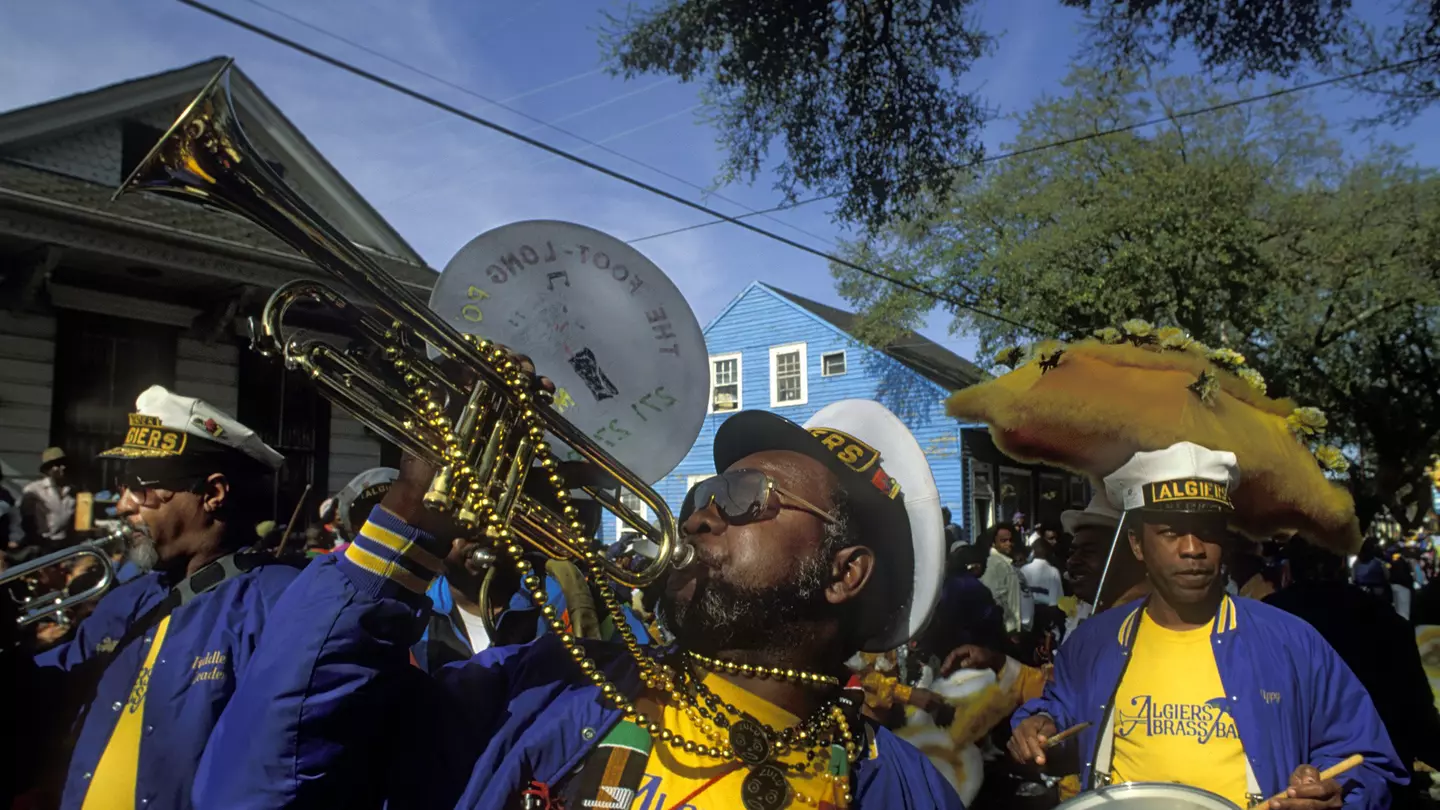 Musicians in a brass marching band wearing bright colors and beads.