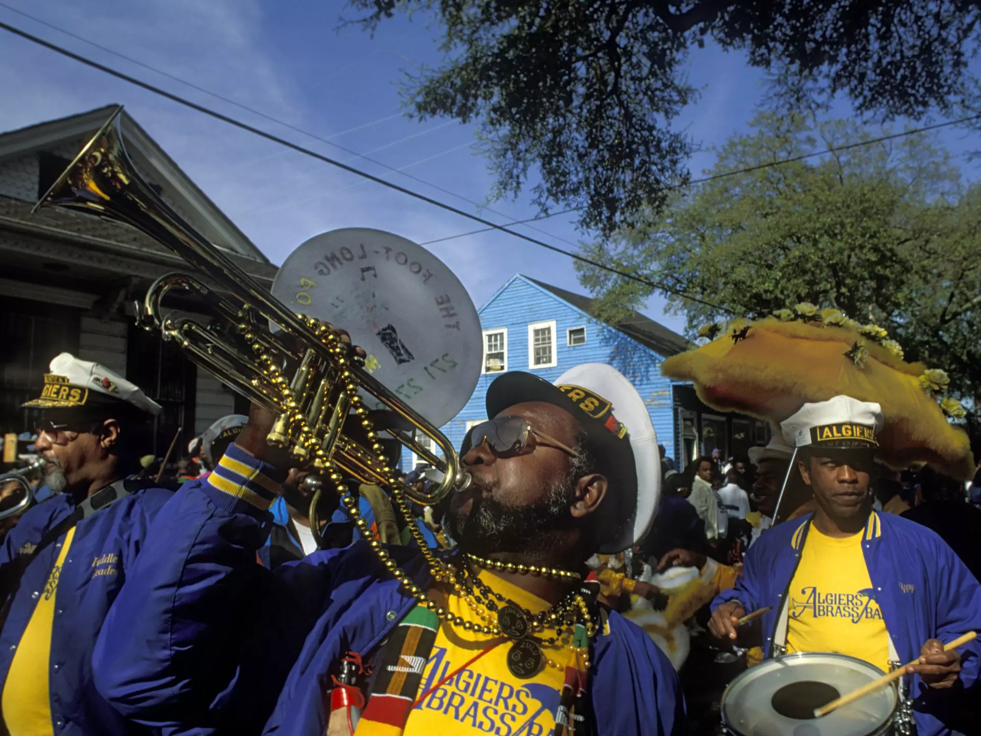 Musicians in a brass marching band wearing bright colors and beads.