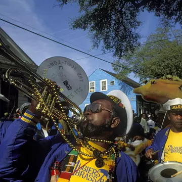 Musicians in a brass marching band wearing bright colors and beads.