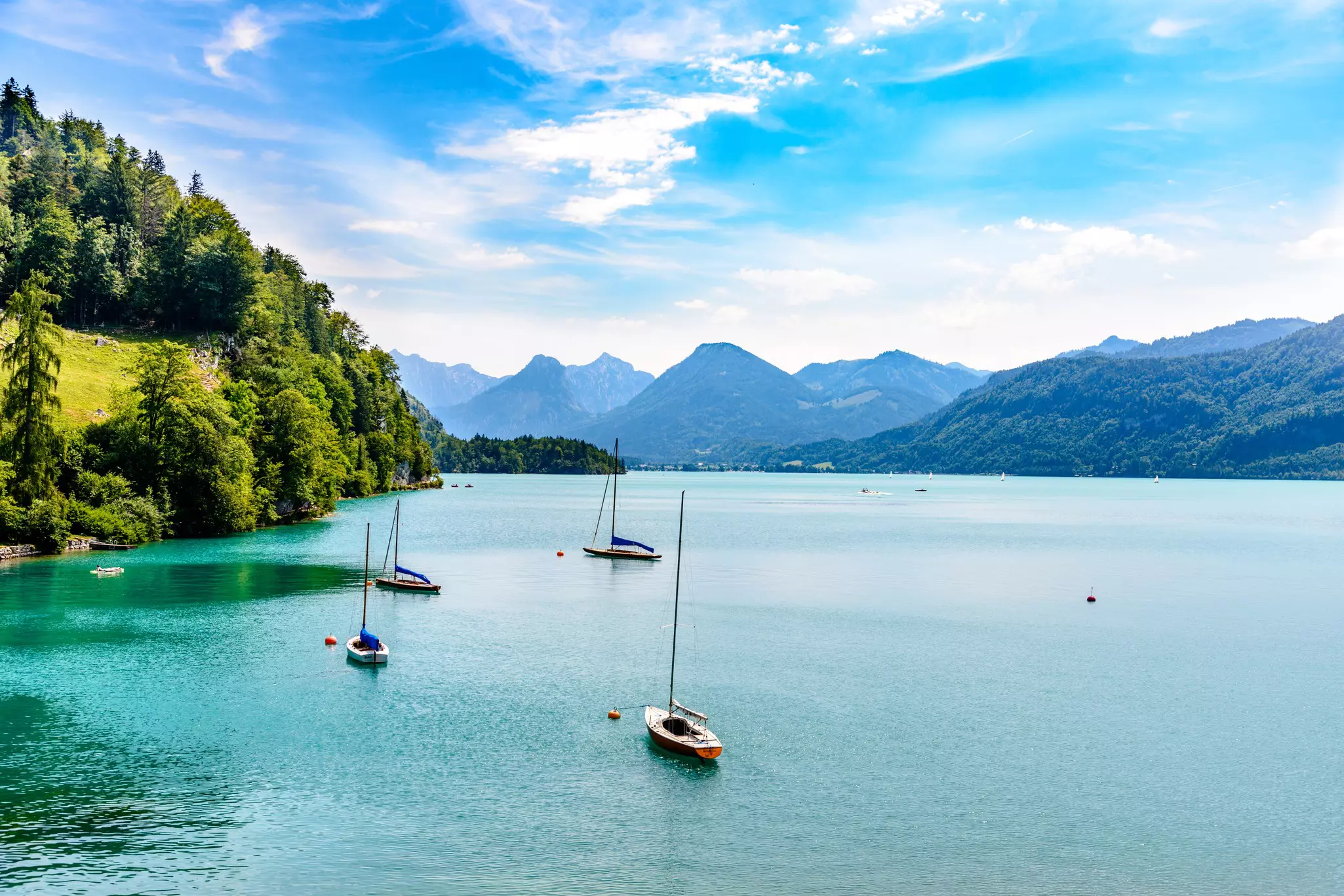 Sailing boats moored in a sparkling mountain lake.