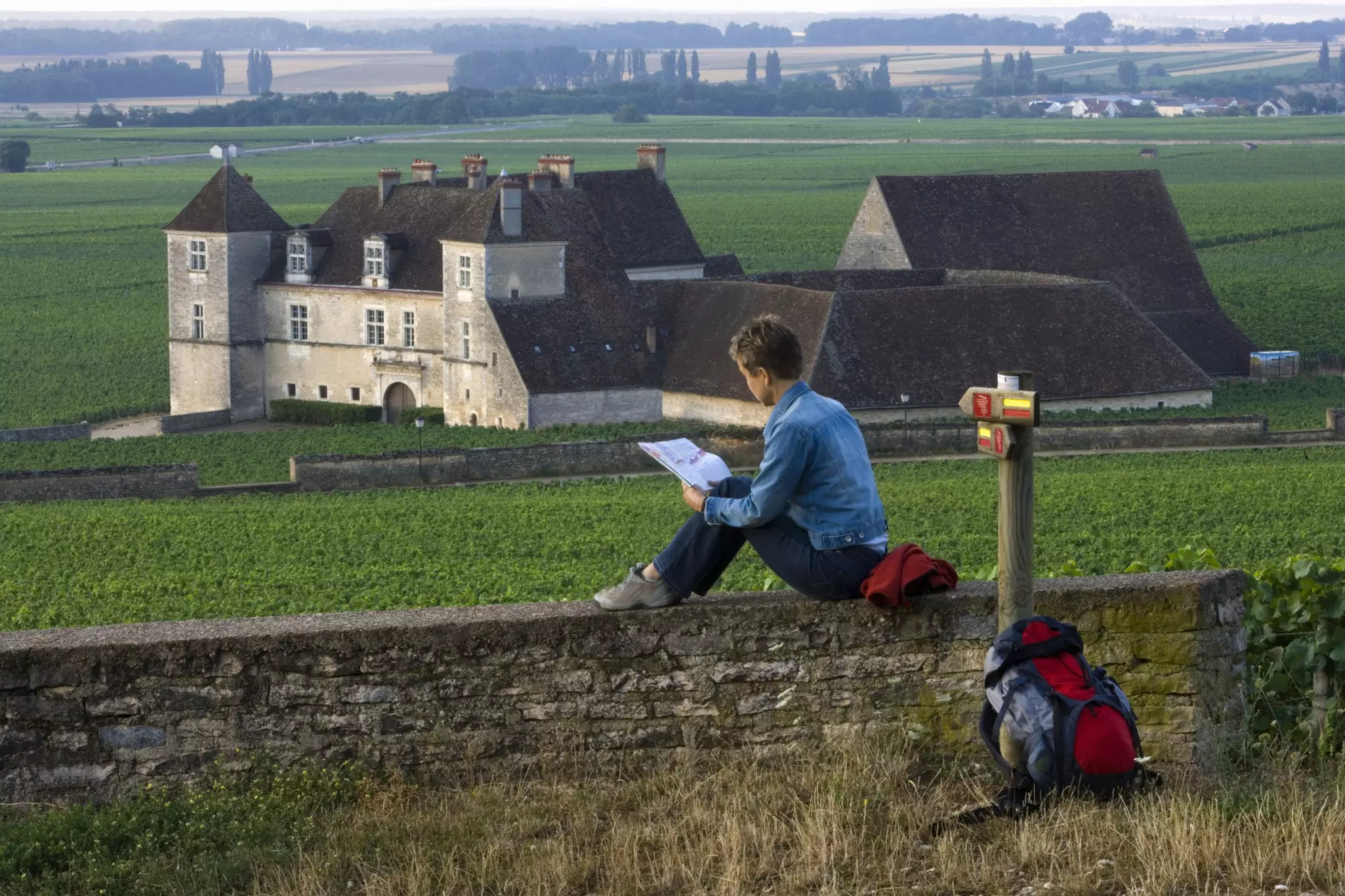 A woman hiker pauses at Castle Clos de Vougeot near Beaune