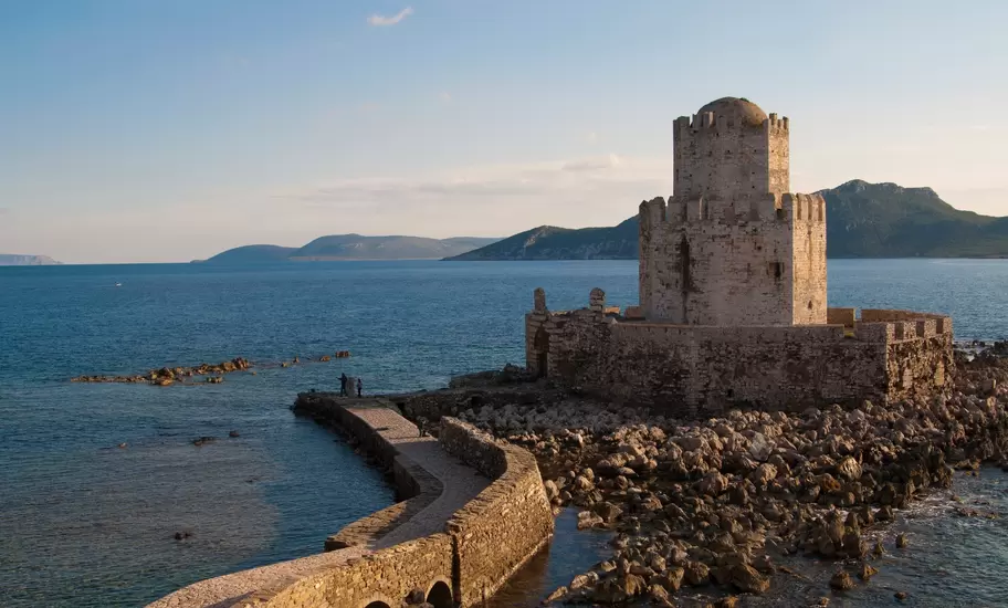 Octagonal Bourtzi tower of Methoni Castle in Messinia on a rocky islet, linked by a stone causeway, hills across the sea